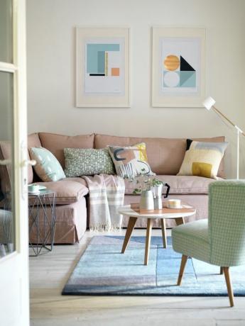 ružičasti kauč zelena fotelja i plavi rugart klasi uokvireni grafički printovi i jastuci s modernim umjetničkim dizajnom pružaju upečatljiv kontrast prigušenoj paleti pastelnih boja