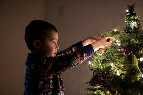 Dječak ukrašavajući božićno drvce kod kuće