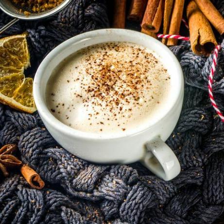 jesenski slatki topli napitak, chai maslacem namazan maslac, pita od buče ili začin od bundeve kava latte ugodna jesenska pozadina s tradicionalnom latte šalicom, začinima i starim džemperom, na rustikalnoj drvenoj podlozi