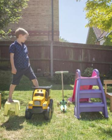 dječak hoda po igračkama raspoređenim u dvorištu