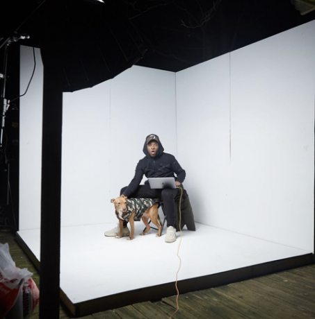 čovjek sjedi u bijelom foto studiju, a pas je pokraj njega