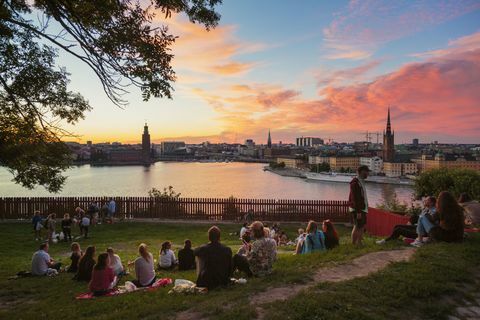 Ljudi koji izlaze u pikniku u parku s panoramom Stockholma za vrijeme zalaska sunca, Švedska