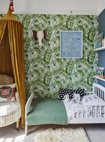 dječja spavaća soba s tapetama s uzorkom tropske palme i žutim baldahinom