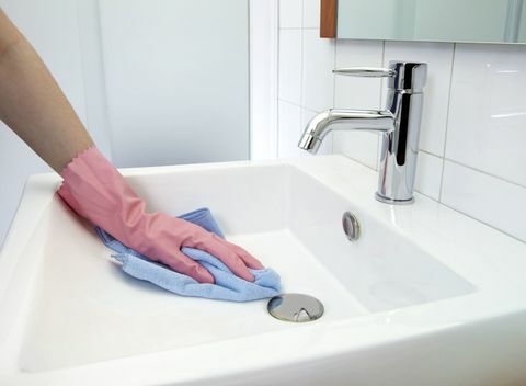 Čišćenje umivaonika: Žena koja čisti umivaonik krpom i rukavicama od mikrovlakana