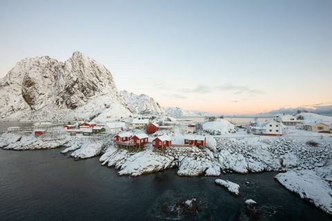 Selo crvene ribarske kuće među snijegom s pogledom na planinu na otoku Lofoten Hamnoy u Norveškoj