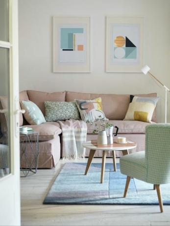 bijela dnevna soba, sa svijetloružičastim kaučem, malim okruglim stolićem, plavim tepihom, zelenom stolicom i slikama na zidu