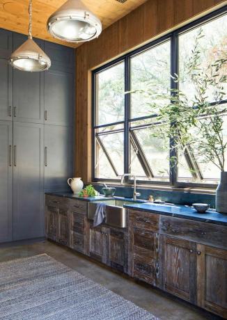 kuhinjski sudoper, drveni ormarići i otvoreni prozori