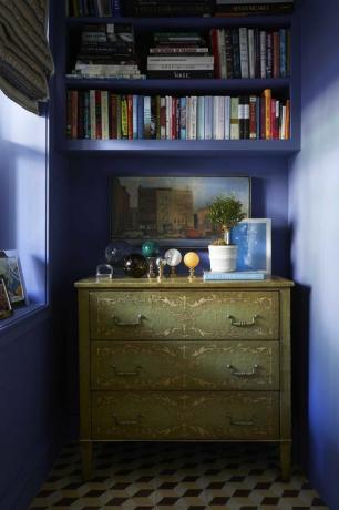 plavo obojeni zidovi, zelena komoda, mramorne kugle, ukrasne knjige, bijela biljka u saksiji