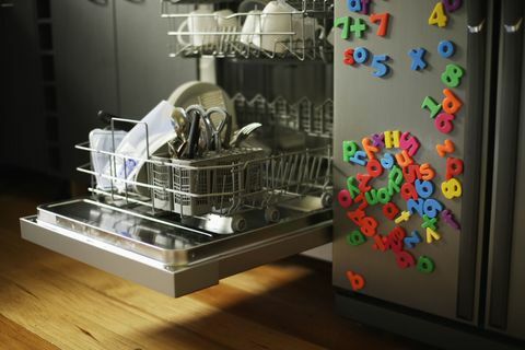 Stroj za pranje posuđa s otvorenom ladicom uz hladnjak pokriven dječjim magnetima za hladnjak