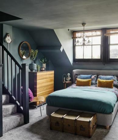 tamnoplava siva spavaća soba u potkrovlju s lusterom i tapeciranim krevetom
