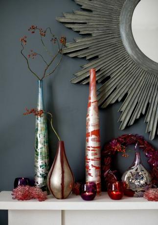 crvene i plave staklene vaze s aranžmanom od grančica, nosači svijeća, kamin, zrcalo, božićni vijenac, svečani, uz sivi zid
