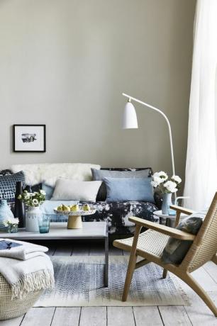 dnevna soba s jastucima na kauču s plavim uzorkom, bijelom podnom svjetiljkom nagnutom nad sofom kaplje kapaka, mrlja uzorcima pijeska za animresionistički izgled koji je suvremen i opušten