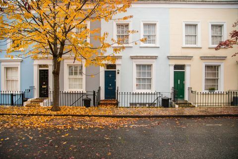 Kuće iz susjedstva Notting Hill, fasada pastelne boje lijepe kompozicije bez automobila i stablo s jesenskim lišćem na tlu u gradu Londonu. Ujedinjeno Kraljevstvo, Europa.