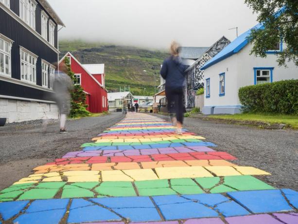 island, seydisfjordur, ljudi hodaju duž asfaltne ceste duginih boja usred osamljenog grada