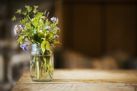 Zatvorite staklenu posudu s malom hrpom divljih cvjetova na drvenom stolu.