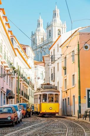 žuti tramvaj u uskoj ulici četvrti Alfama u lisabonu, portugal