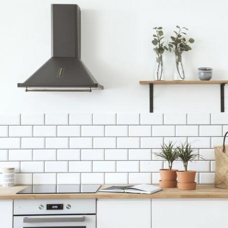 Moderni skandinavski otvoreni prostor s kuhinjskim dodacima, biljkama, drvenom policom i vrećicom od slame. Dizajnerska soba sa zidovima od bijele opeke.